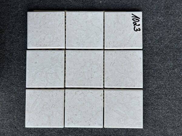 Foto einer einzelnen quadratischen Mosaik-Fliese in beiger Farbe, leicht marmoriert.