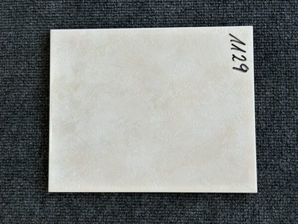 Foto einer einzelnen Wandfliese in beiger Farbe, leicht marmoriert, mit Naturkante.