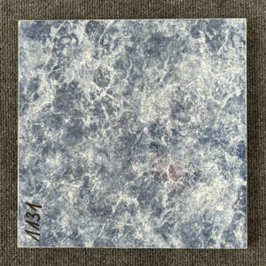 Foto einer einzelnen quadratischen Bodenfliese in dunklem Blau, stark marmoriert und glasiert, mit Naturkante.
