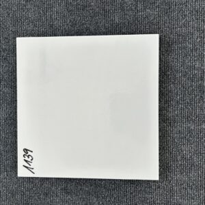 Foto einer einzelnen quadratischen Bodenfliese in glänzendem Weiß, ganz leicht marmoriert, mit Naturkante.