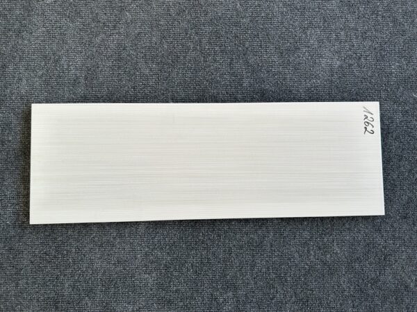 Foto einer einzelnen Wandfliese in grauer Farbe mit Holzoptik, die das Format 20cm x 60cm hat.