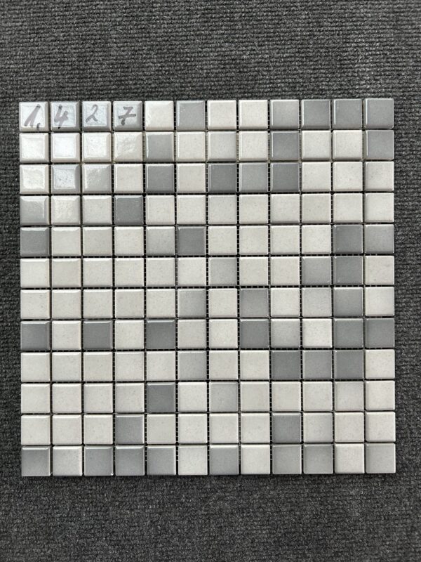 Foto einer einzelnen, quadratischen Mosaik-Fliese. Die Felder der Mosaik-Fliese sind in verschiedenen, glänzenden Grautönen gehalten.