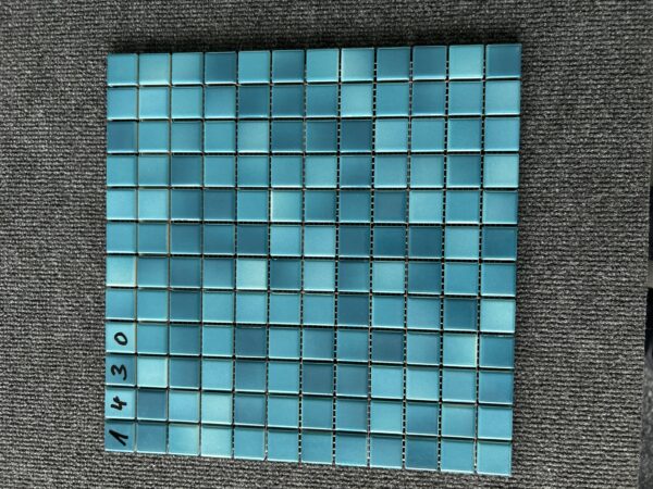 Foto einer einzelnen, quadratischen Mosaik-Fliese. Die Felder der Mosaik-Fliese sind in blauen und grünen Farbtönen gehalten.