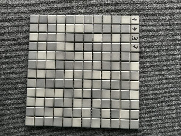 Foto einer einzelnen, quadratischen Mosaik-Fliese. Die Felder der Mosaik-Fliese sind in verschiedenen, matten Grautönen gehalten.