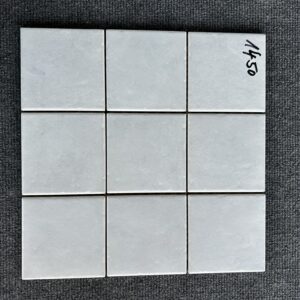 Foto einer einzelnen, quadratischen Mosaik-Fliese. Die Felder der Mosaik-Fliese sind in einem grauen Farbton gehalten.