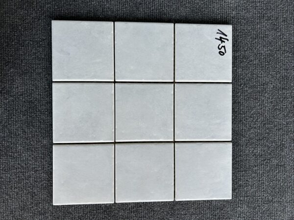 Foto einer einzelnen, quadratischen Mosaik-Fliese. Die Felder der Mosaik-Fliese sind in einem grauen Farbton gehalten.