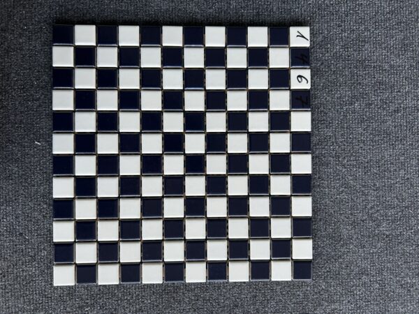 Foto einer einzelnen, quadratischen Mosaik-Fliese. Die Felder der Mosaik-Fliese sind abwechselnd in einem creme blauen und weißen Farbton gehalten.