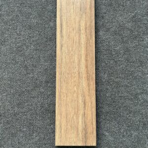 Foto einer einzelnen Bodenfliese Feinsteinzeug im Format 15 cm x 60 cm und Farbton braun. Die Fliese weist eine Holzoptik auf.