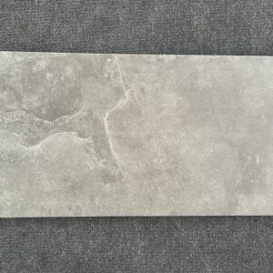 Foto einer einzelnen Bodenfliese Feinsteinzeug im Format 45 cm x 90 cm und dunkelgrauem Farbton. Die Struktur verleiht der Fliese eine natürliche Steinoptik.