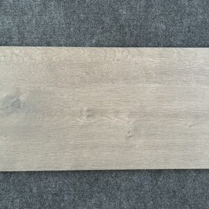 Foto einer einzelnen Bodenfliese Feinsteinzeug im Format 30 cm mal 60 cm. Die Fliese ist in einem hellen Braun gehalten und optisch Holz nachempfunden.