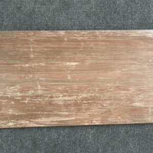 Foto einer einzelnen Bodenfliese Feinsteinzeug im Format 45 cm x 90 cm Diese Fliese hat einen rötlichen, anpolierten Braunton gehalten, der teilweise glänzend und teilweise matt erscheint. Die Fliese hat eine Holzoptik, die kaum von echtem Holz zu unterscheiden ist.