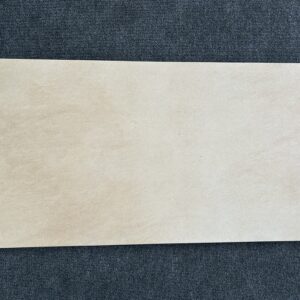 Foto einer einzelnen Bodenfliese Feinsteinzeug im Format 45 cm x 90 cm. Farblich ist die Fliese beige anpoliert, das heißt, dass sie teilweise glänzendes und teilweise mattes Beige aufweist.