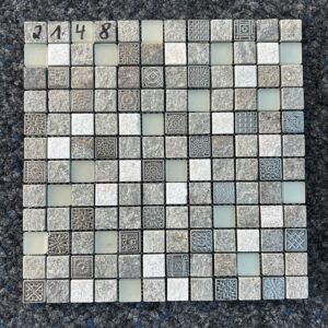 Foto einer einzelnen, quadratischen Mosaik-Fliese. Die Felder der Mosaik-Fliese sind in verschiedenen Grautönen gehalten und zeigen verschiedene Muster, die an Steine und Schmuckstücke erinnern.