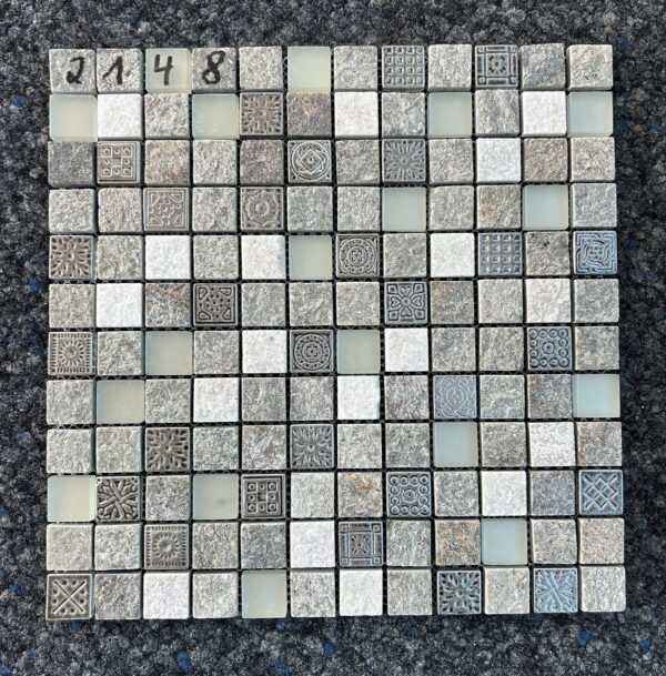 Foto einer einzelnen, quadratischen Mosaik-Fliese. Die Felder der Mosaik-Fliese sind in verschiedenen Grautönen gehalten und zeigen verschiedene Muster, die an Steine und Schmuckstücke erinnern.